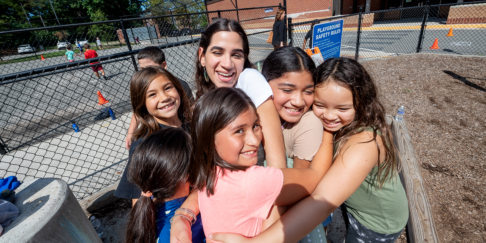 ​  Third grade Spanish immersion teacher Gabriela Muriente is hugged by her students on the playground  ​